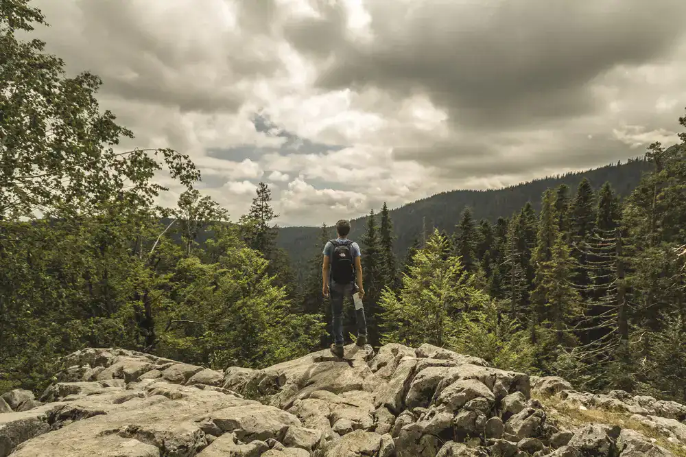 Hiker organizing gear on a rocky outcrop